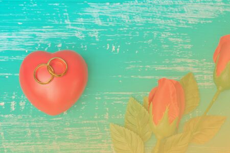 wedding ring and red heart on wood
