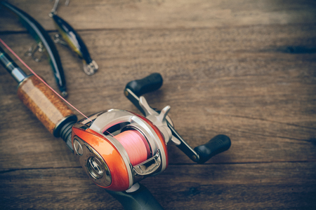 Fishing tackle - Baitcasting Reel, hooks and lures on  wooden backgroundの写真素材