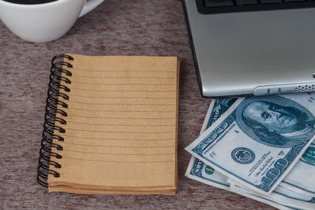 book note and laptop on table with moneyの写真素材