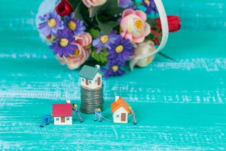 miniature worker and small house on coin stack