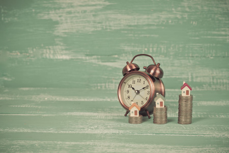 Mini houses on coin stack with alarm clockの写真素材