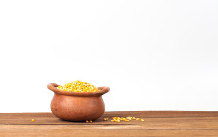 Corn seeds in clay pot on wooden tableの写真素材