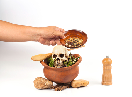 boiled skull in clay pot with some herb on whiteの写真素材