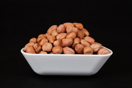 ground nut in white dish on black background