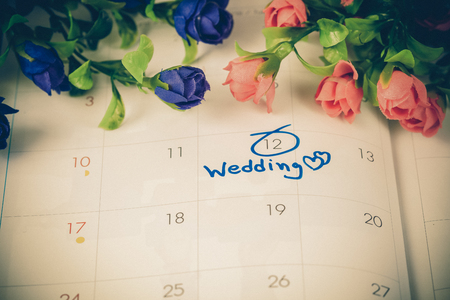 Wedding note on a calendar sets a reminder for the wedding day with flower.の写真素材