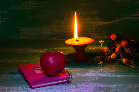 still life candlestick with heart sign on old bookの写真素材
