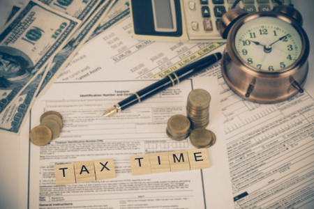 wording tax and calculator with tax documents, money and alarm clock on table. Tax concept.の写真素材