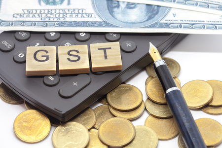 Word of GST on wooden alphabet blocks on calculator .Selective focus,shallow depth of field. Finance and tax concepts.の写真素材