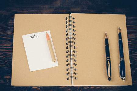 Two vintage fountain pens over a dairy book on wood table.の写真素材