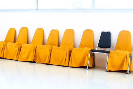 A row of yellow chairs and blue chair insert in row.の写真素材