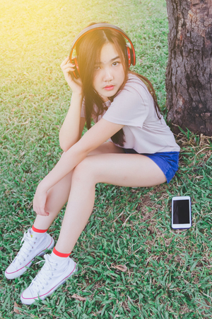 Lady listening music from smart phone with headphones outdoor at a park.の写真素材