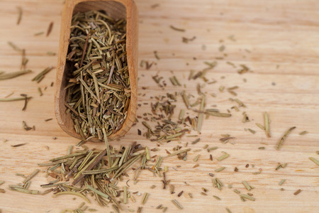 dry rosemary herb in wood scoop on wood background.の写真素材