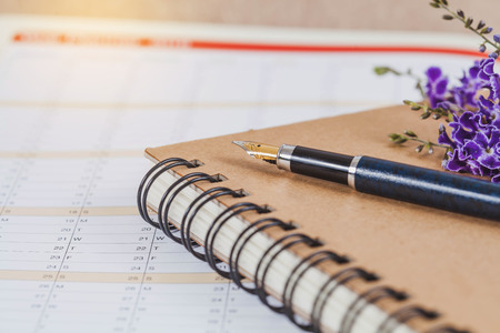 personal organizer or planner with fountain pen on wood table.