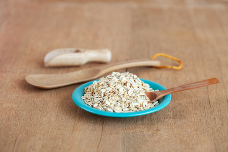 Oats flakes in dish on wood tableの写真素材