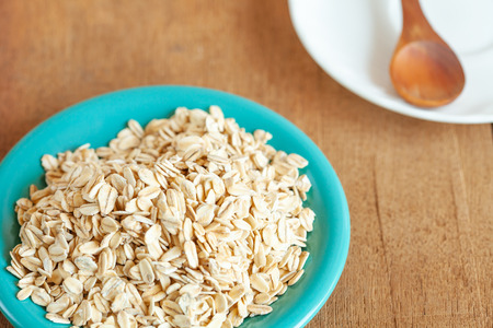 Oats flakes in dish on wood tableの写真素材