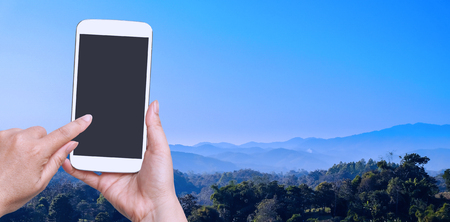 woman hand hold and touch screen smart phone on landscape view.の写真素材