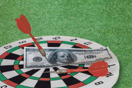 Dart arrow hitting in bullseye on dartboard with moneyの写真素材