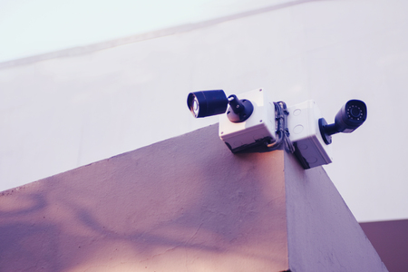 CCTV or video camera with illumination is hanging on the wall. on top of buildingの写真素材