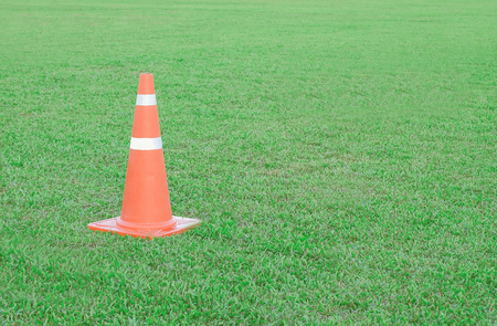 Traffic cone or funnel on green field background.の写真素材