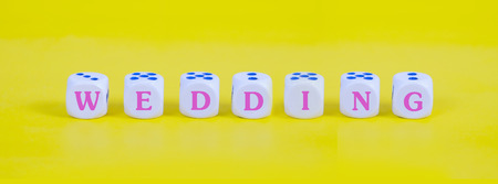 Wedding word on white dice on color background, love concept.の写真素材