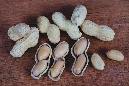 Peanuts in shells on wood table background.