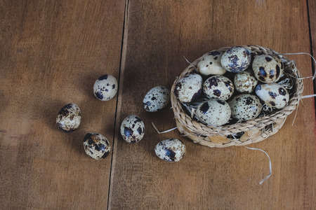 Quail eggs in bamboo basket On the old wood table background.