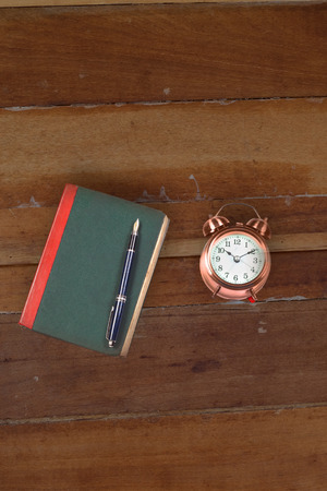 Old text book with alarm clock on dirty wood table.

の写真素材
