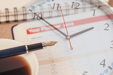 personal organizer or planner with fountain pen and hot coffee on clockの写真素材