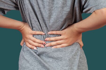 Woman feeling back pain, massaging tense muscles,Aches and pains concept.