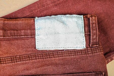 Old Leather label on color denim background closeup.
