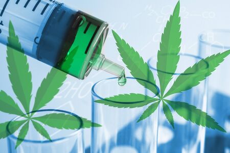 Syringe dropping a chemical solution into a test tube on soft light background.の写真素材