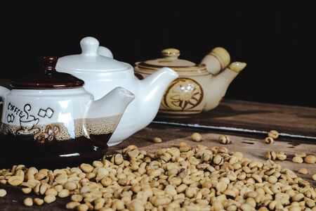 Traditional Teapot with raw coffee beans on wood table.の写真素材