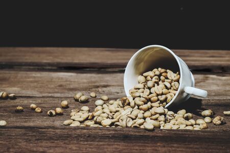 Organic Raw coffee beans in coffee cup on wood table.

の写真素材