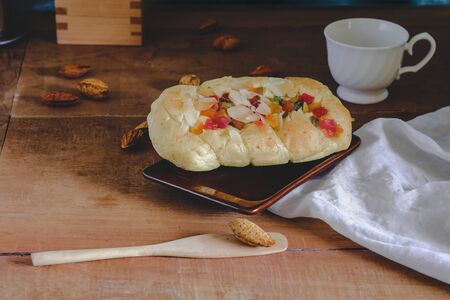 Mixed fruit bread with almond flakes on color wood background,food concept.