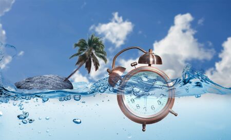 A  alarm clock  into water with a rocky island and coconut tree in the background. Concept  time not important on vacation.の写真素材