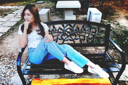 Young woman sitting in coffee shop at park bench.の写真素材