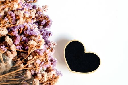 Black woodden heart with dry flower on white background.の写真素材