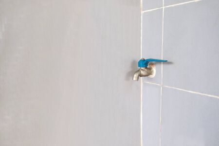Small blue water tap on wall background.の写真素材