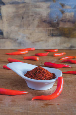 Chili powder and fresh peppers on old wood table background.の写真素材