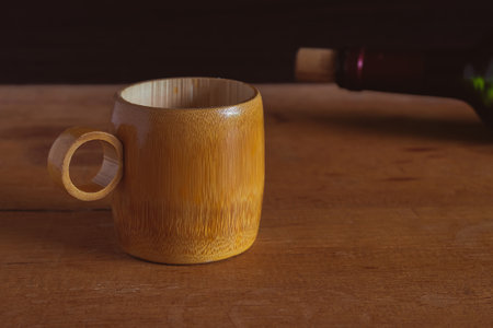 Bamboo cup with wine bottle on wood background.の写真素材