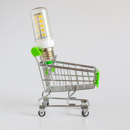 Green Supermarket shopping cart with light blub on white.の写真素材