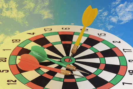Dart arrow on dart board over blue sky background.