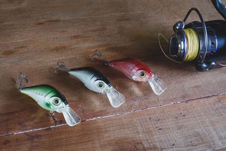 Fishing tackle - fishing spinning, hooks and lures on wooden table.の写真素材