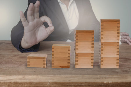 Businessman hand arranging wood cube stacking as step stair. Business concept.の写真素材