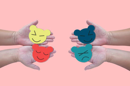 Hand holding color paper cut with face sign on color background .の写真素材