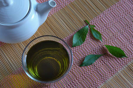 Fresh green tea with tea leaves and tea pot .の写真素材