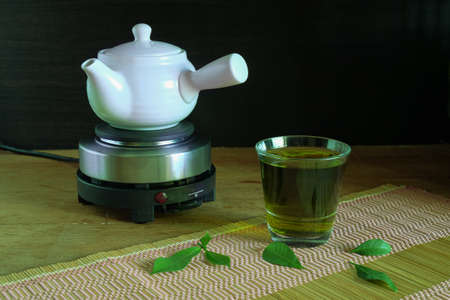 Fresh green tea with tea leaves and tea pot .の写真素材