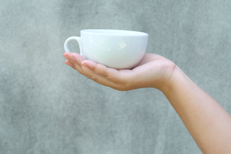 hand holding a cup of coffee on wall background.の写真素材