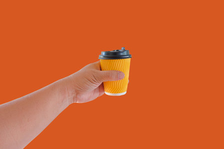 Hand hold a hot drink in to go paper cup.