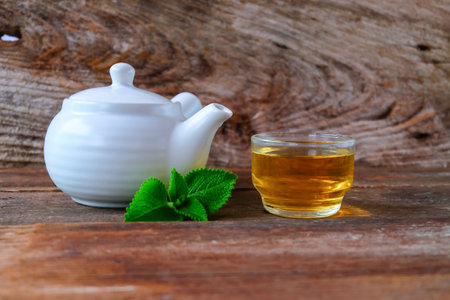 White teapot and cup of hot beverage on wooden.の写真素材